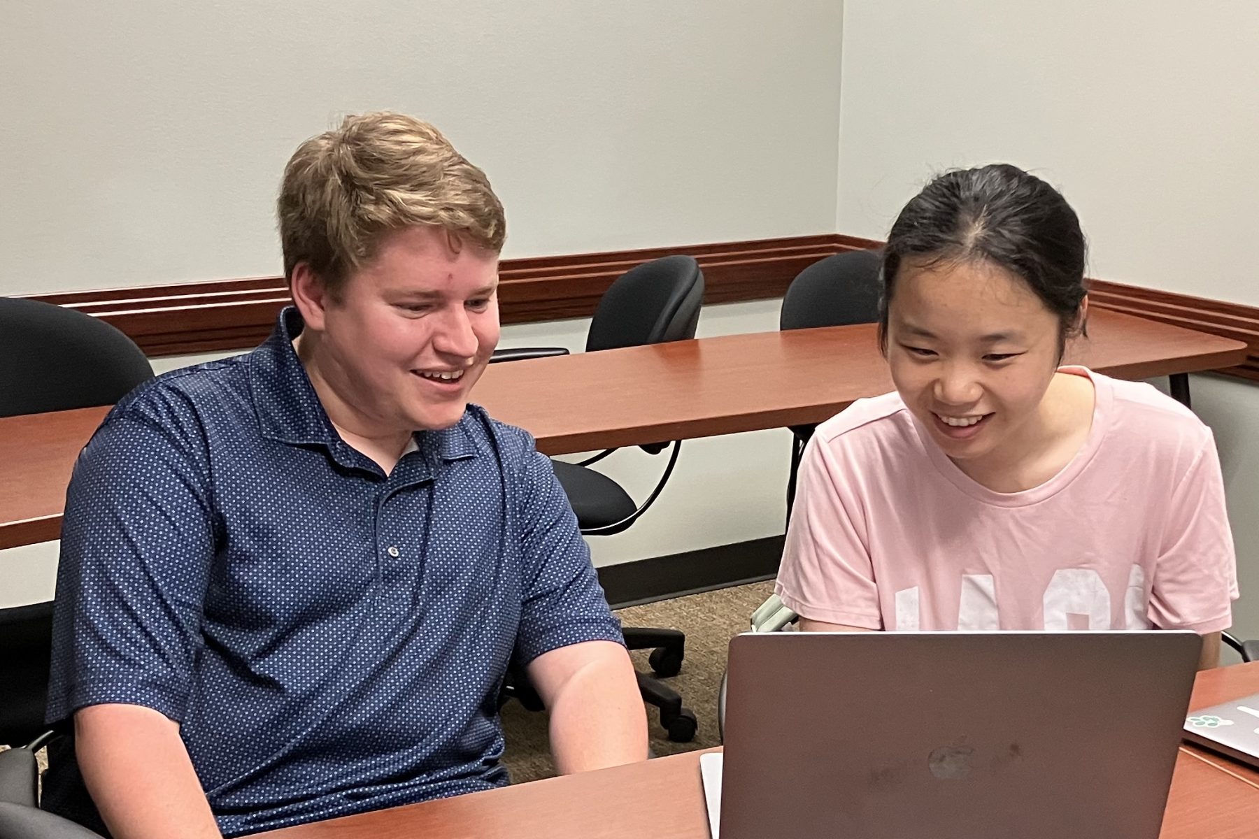 Two students in discussion while looking at a laptop screen
