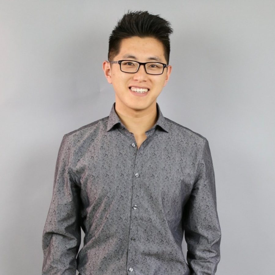 Chinese American man with short black hair and glasses in a black and gray collared shirt