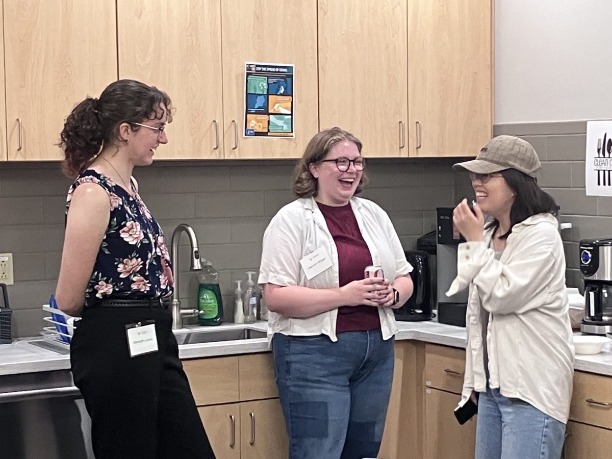 Three students laughing in a break room corner