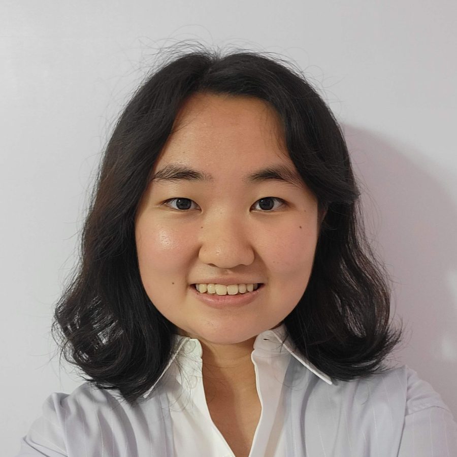 Asian American woman with shoulder-length black hair, in white blouse with high open collar