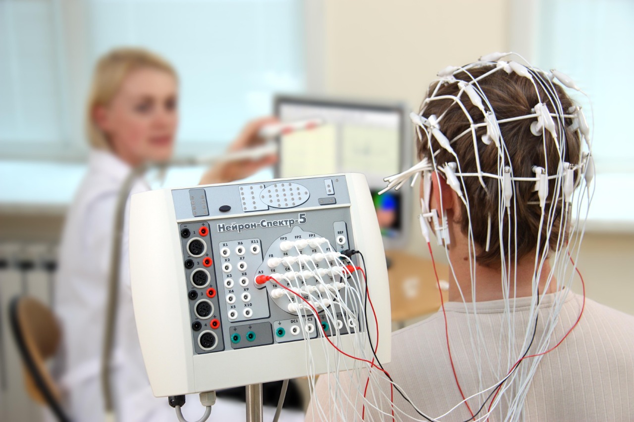 A person with an eeg electrode cap being monitored by a nurse