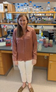 Woman standing in front of lab bench smiling
