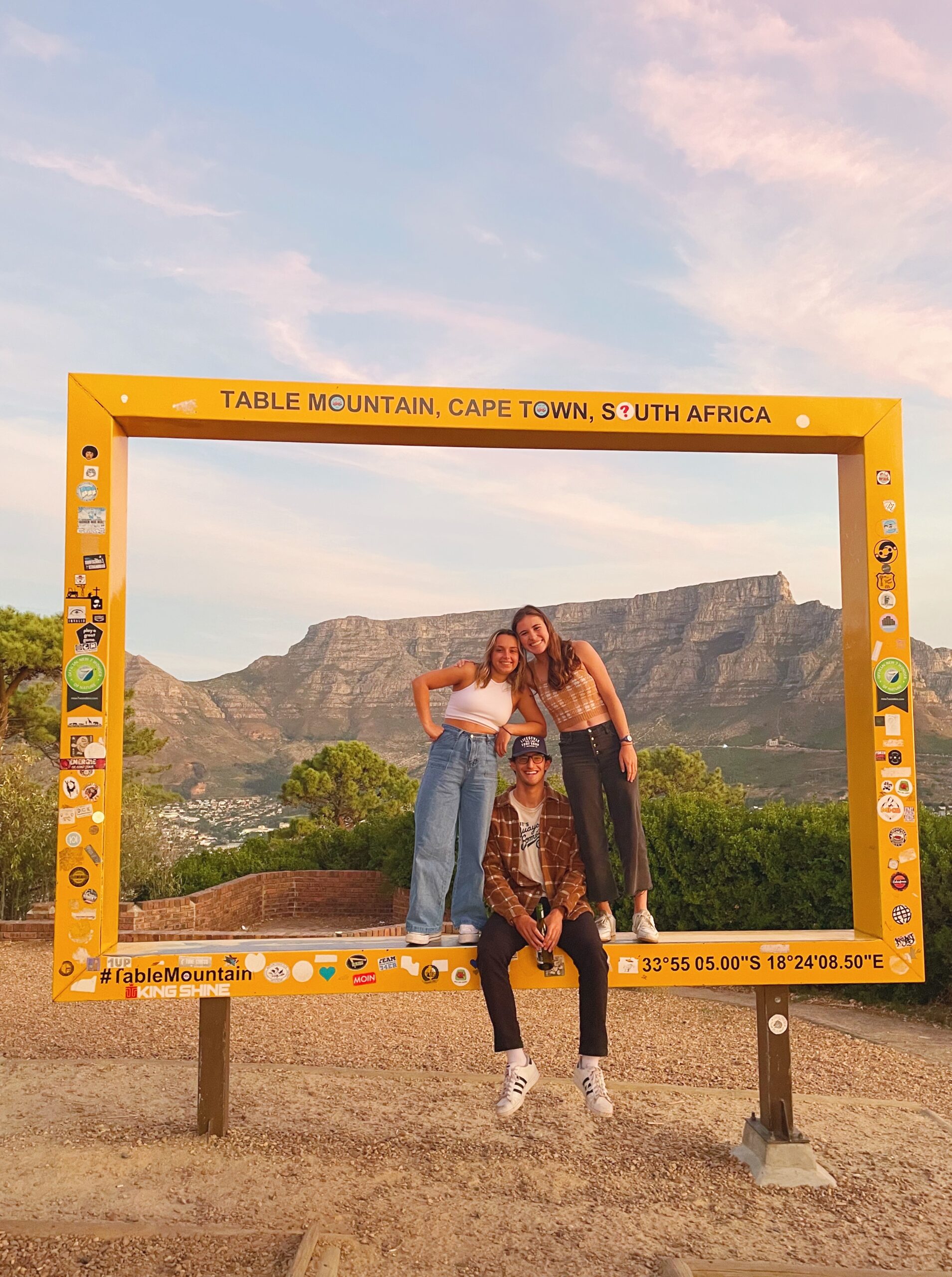 Three students inside a large rectangular frame marking a view of Cape Town's Table Mountain