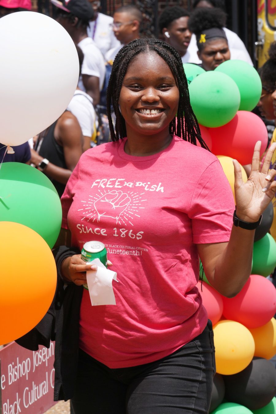 Student smiling and waving at Juneteenth 2023 celebration.